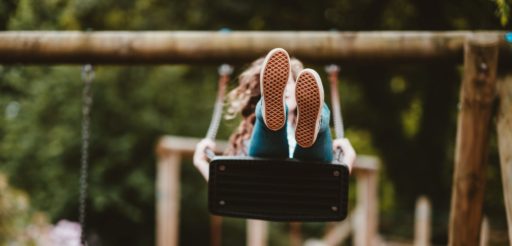 soles of a child's sneakers as they swing towards the viewer on a park swing